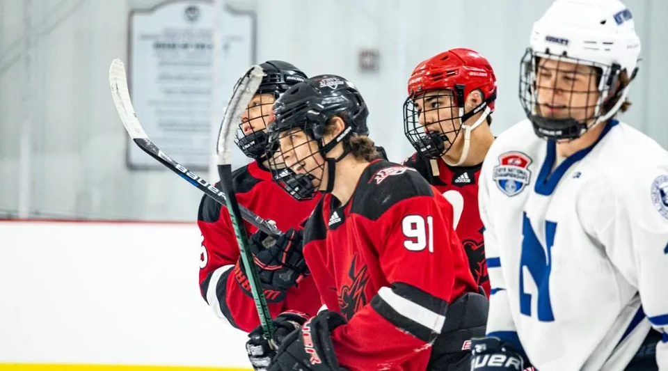 Un gruppo di giocatori di hockey in maglie rosse e blu sulla pista di ghiaccio della South Kent School.