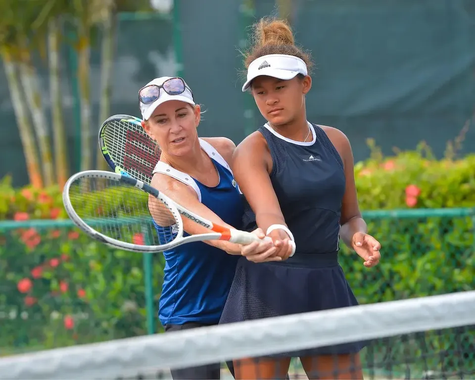 Un'allenatrice della Evert Tennis Academy aiuta una giovane giocatrice a impugnare la racchetta da tennis sul campo.