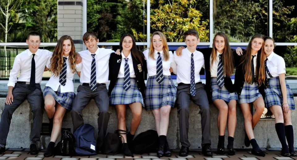 Un gruppo di studenti è insieme nel campus della Glenlyon Norfolk School davanti a edifici e aree verdi.