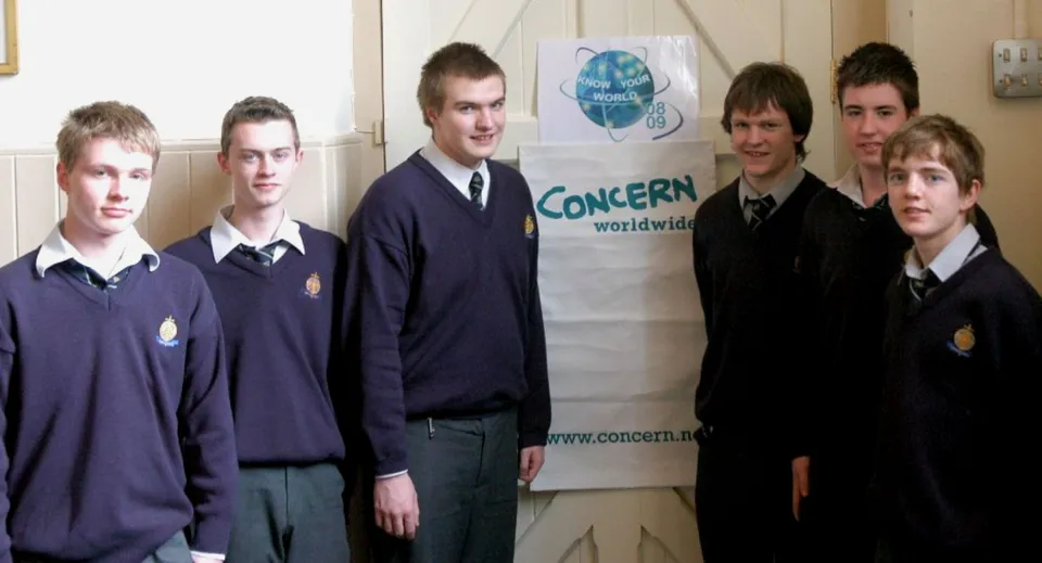 Un gruppo di studenti si trova davanti allo striscione di CONCERN worldwide nel campus del St. Macartan's College.
