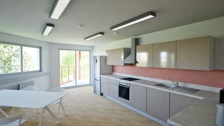 Cocina compartida de la residencia con armarios, horno y mesa de comedor