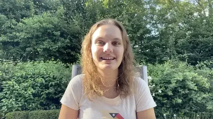 Lisa Marie erzählt vor einer grünen Hecke von ihrem Auslandsjahr, Vorschaubild des Erfahrungsvideos
