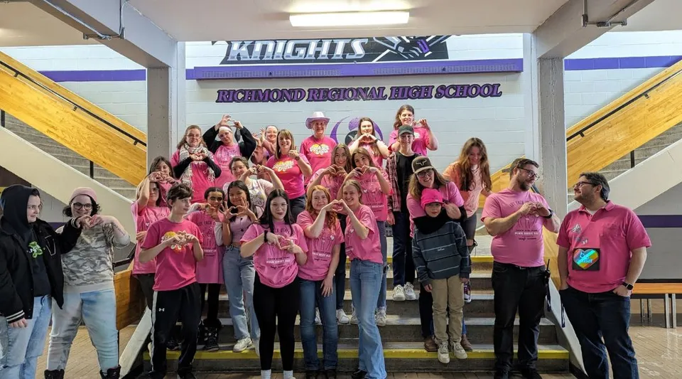 Un gruppo di studentesse sta insieme davanti a uno striscione della Richmond Regional High School.