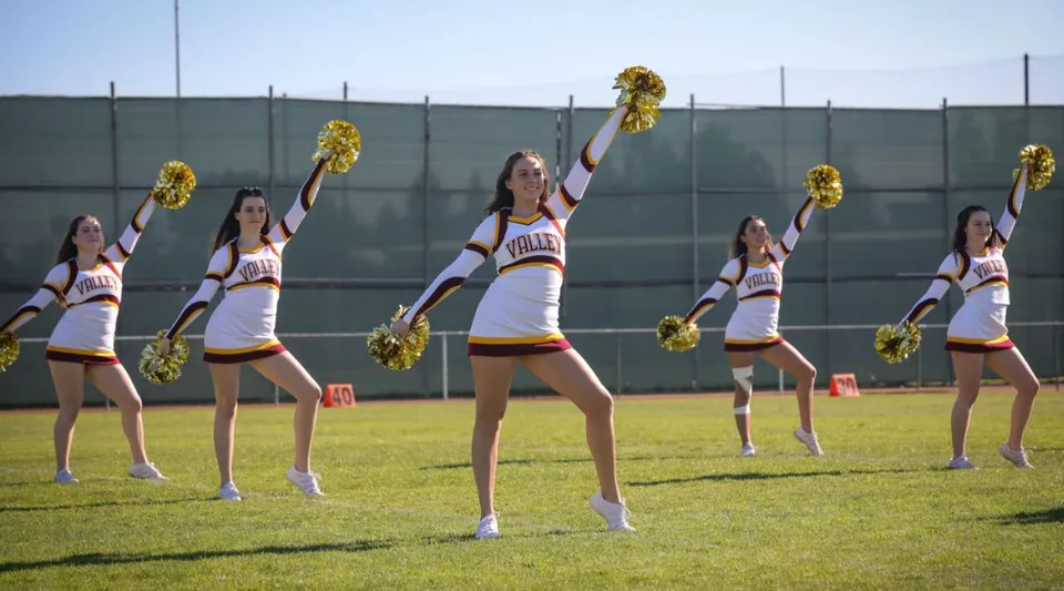 Un gruppo di cheerleader esegue una coreografia sul campo sportivo della Valley Christian High School.