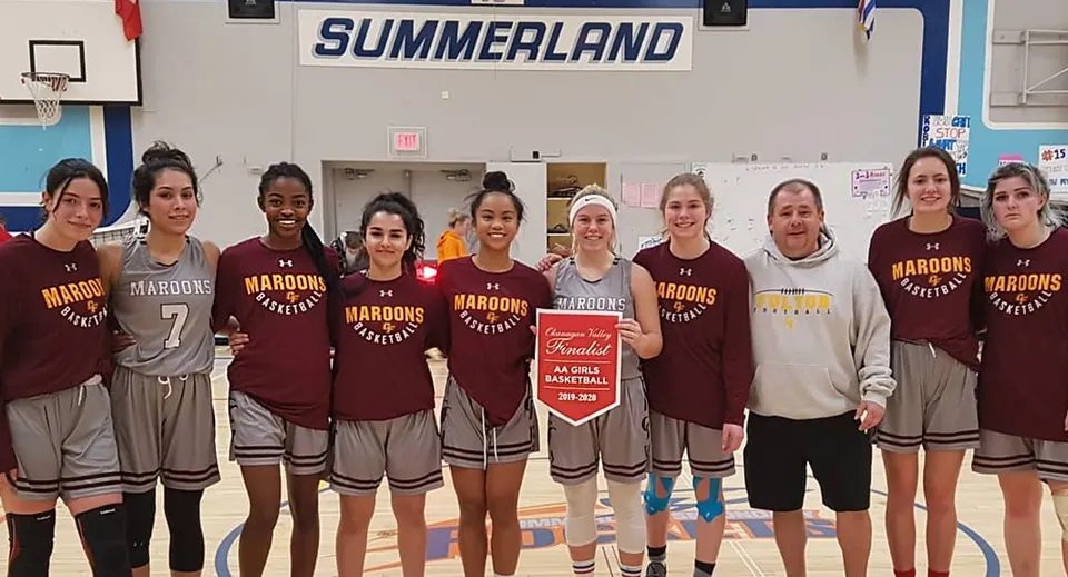 Studentesse della Clarence Fulton Secondary School in divisa sportiva insieme davanti al cartello Summerland.