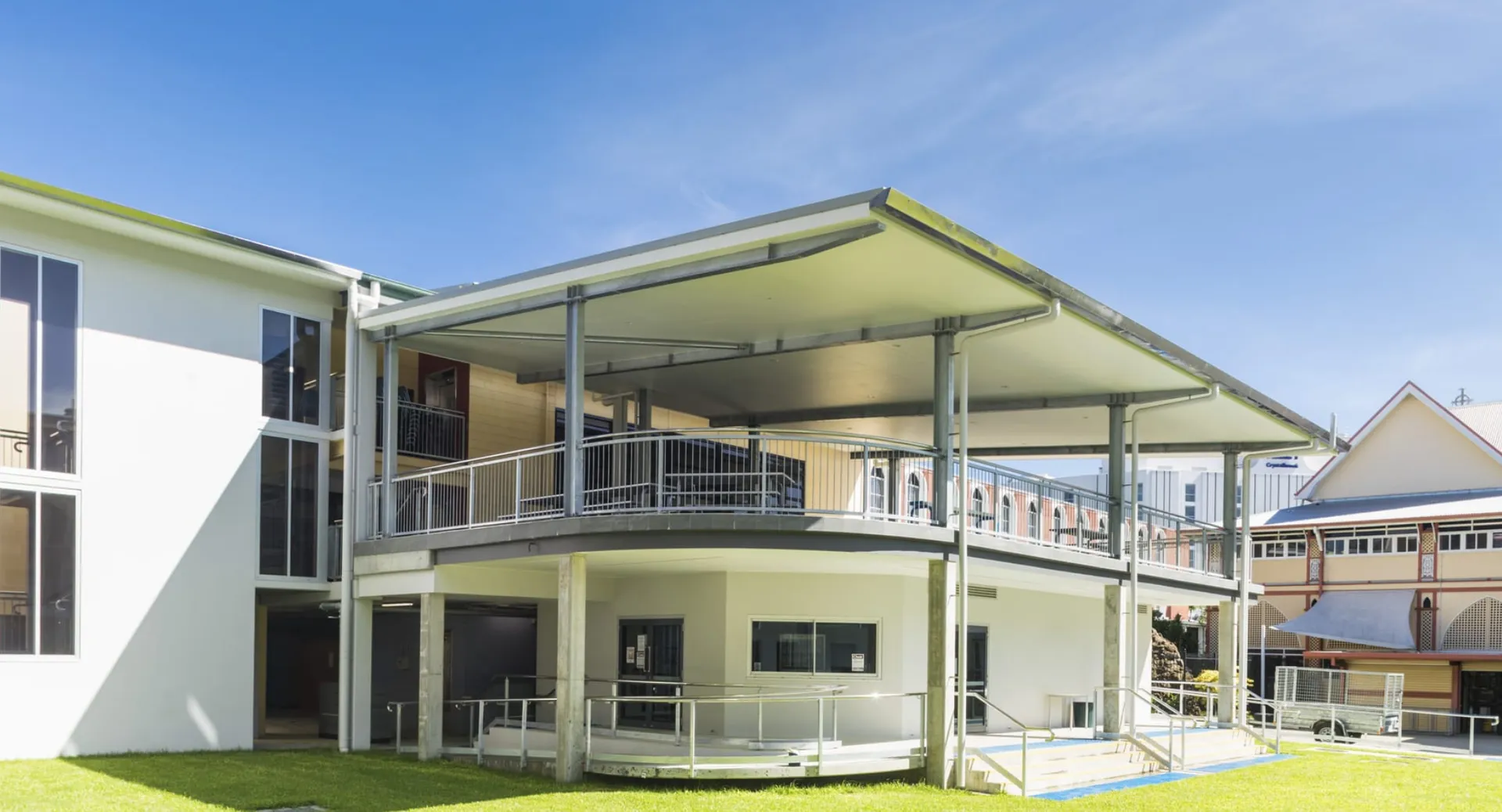 Un edificio residenziale moderno con balcone e prato sotto un cielo limpido all'interno del campus della Mabel Park State High School.