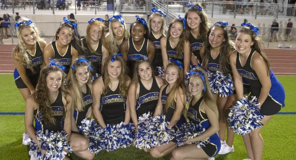 Un gruppo di cheerleader della Lafayette Christian Academy posa insieme con divise abbinate su un campo sportivo.