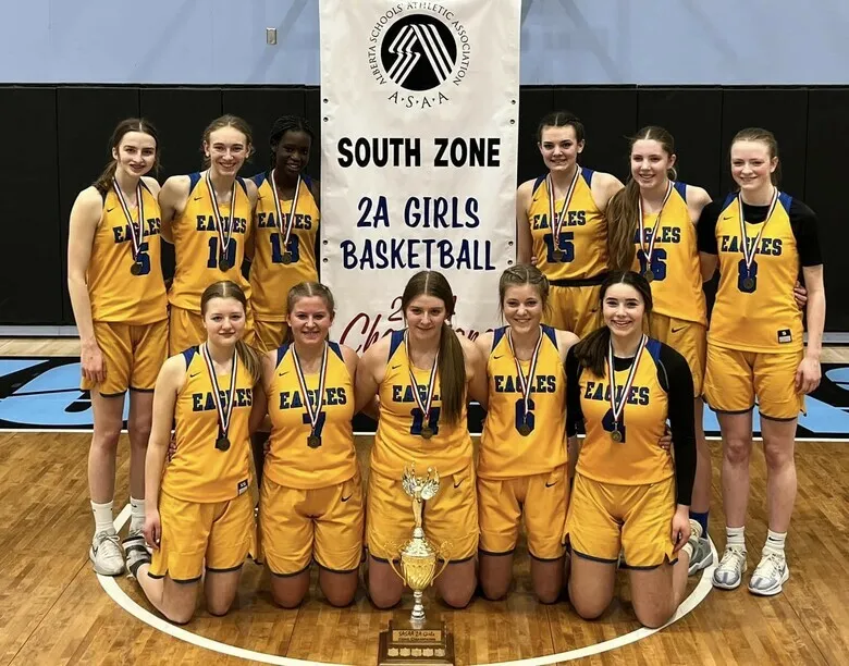 Alumnas de Immanuel Christian Secondary School posan juntas frente a la pancarta South Zone 2A Girls Basketball.