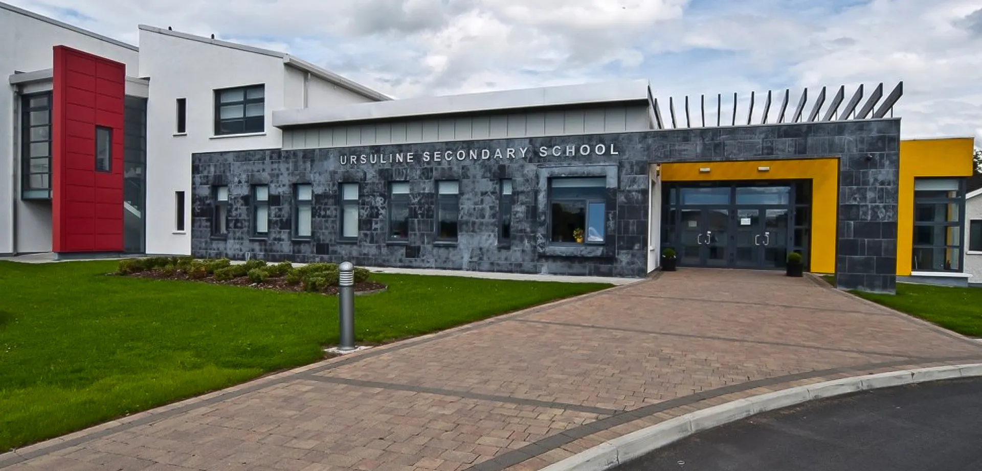 L'edificio moderno della Ursuline Secondary School Thurles con facciata in pietra grigia e ingresso pavimentato.