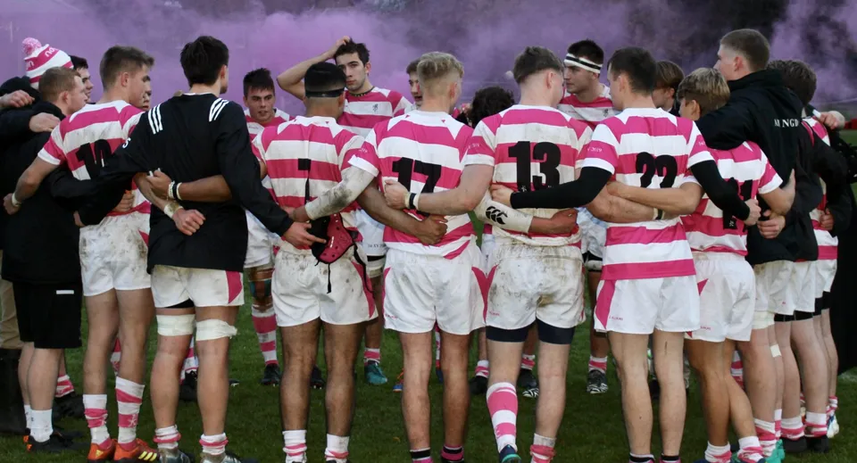 Un gruppo di giocatori di rugby con la maglia della Abingdon School è riunito a stretto contatto sul campo da gioco.
