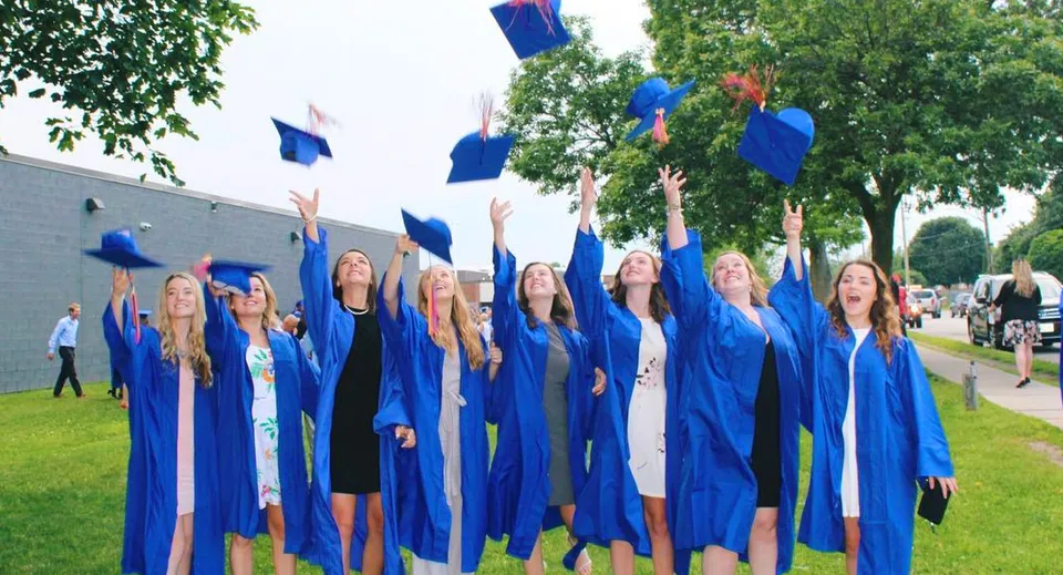 Un gruppo di neodiplomati lancia in aria i propri tocchi blu nel campus della Eastview Secondary School.