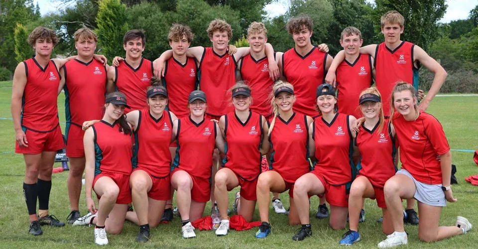Un gruppo di studenti della Lincoln High School in uniformi sportive rosse posa insieme all'aperto davanti a un paesaggio verde.