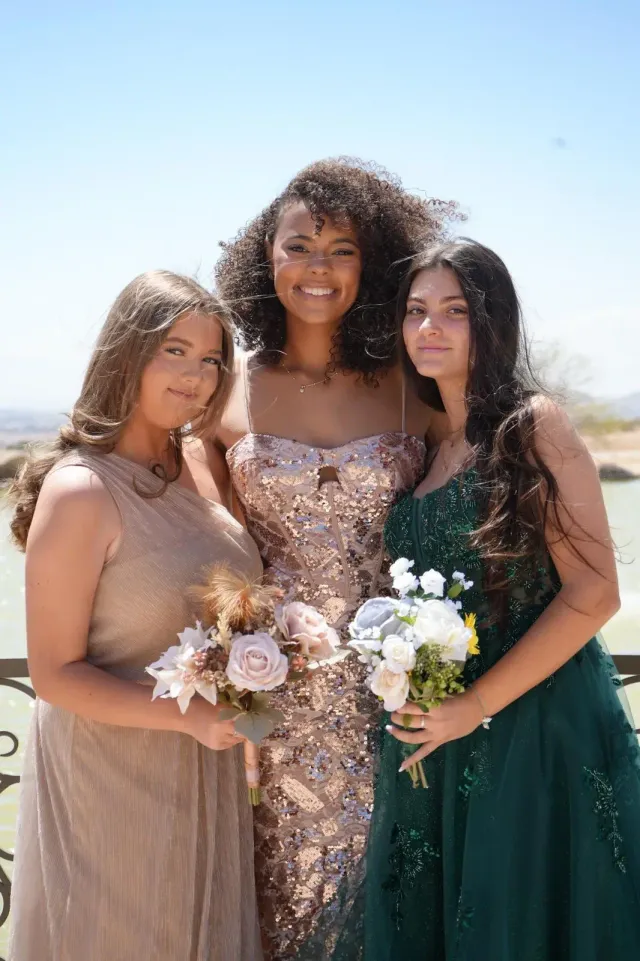 Tres estudiantes con vestido de gala y ramos de flores en Estados Unidos