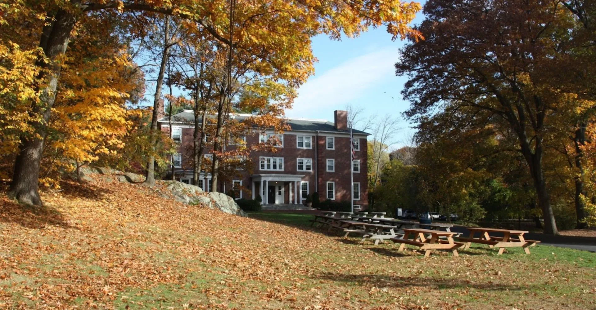 L'edificio storico in mattoni della Chapel Hill - Chauncy Hall è circondato da variopinte foglie autunnali e da una collina erbosa con panchine in legno.