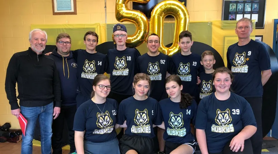 Studenti e insegnanti del Dorset Collegiate si radunano davanti a un grande 50 dorato per festeggiare l'anniversario.