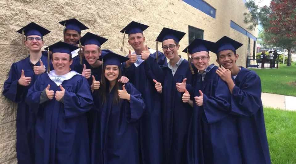 Un gruppo di diplomati della Vanguard School davanti a un edificio in mattoni fa il gesto del pollice in su.
