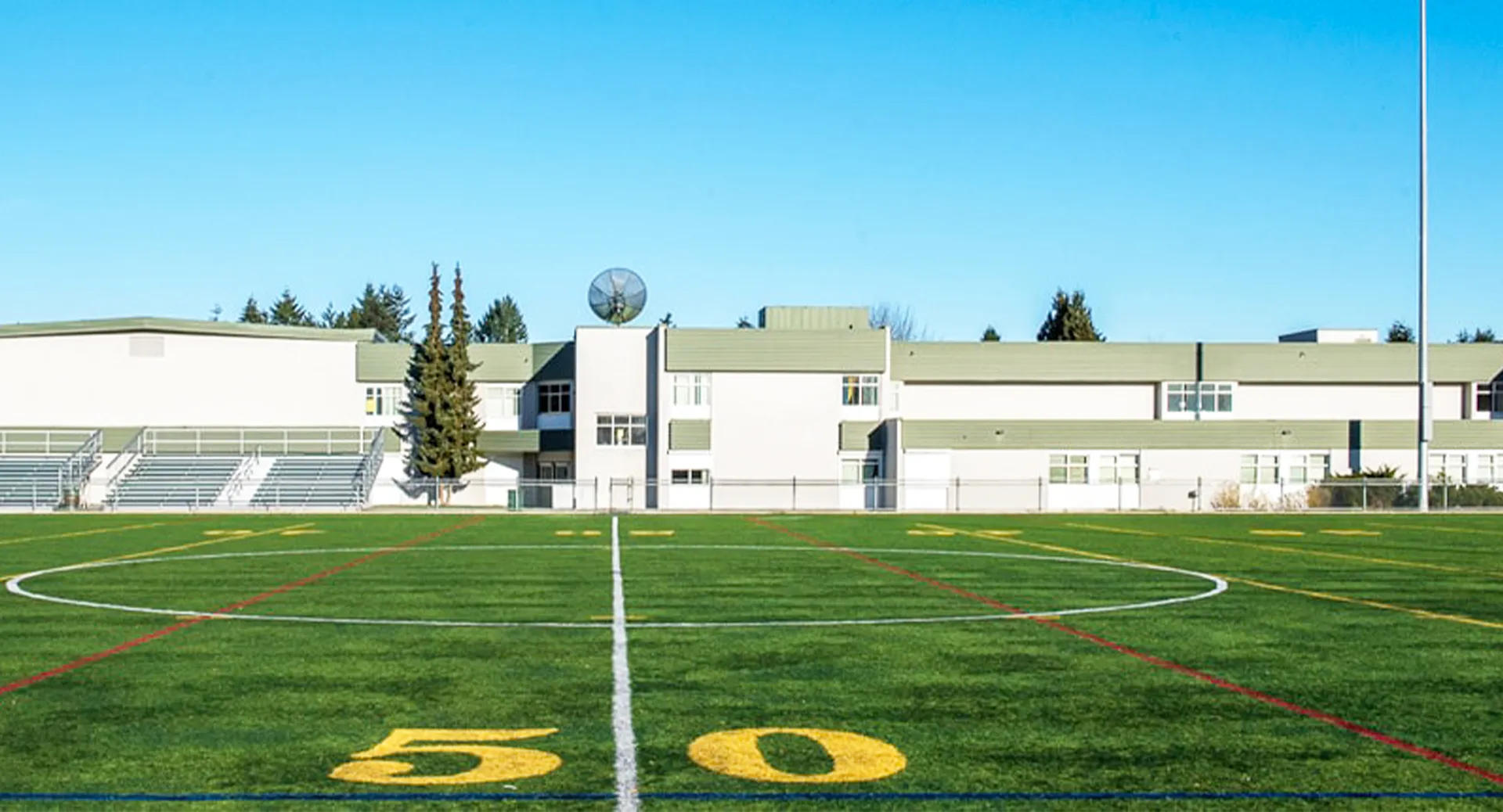 Il campo da calcio della Pitt Meadows Secondary School con una linea delle 50 yard e la struttura di uno stadio sullo sfondo.