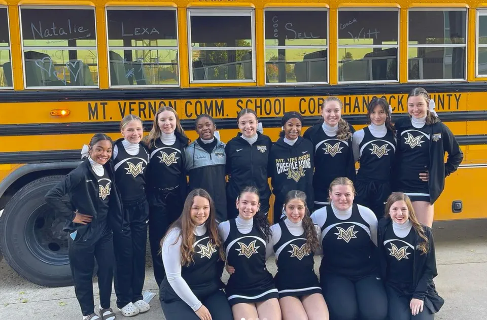 Studenti della Mt. Vernon High School posano in uniforme davanti a uno scuolabus giallo con la scritta Mt. Vernon Comm. School Corp.