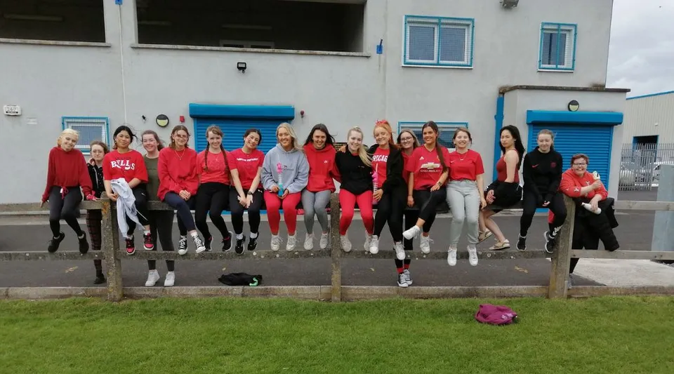 Un gruppo di studentesse sta davanti a un edificio con dettagli blu nel campus della St. Paul's Secondary School a Kildare.