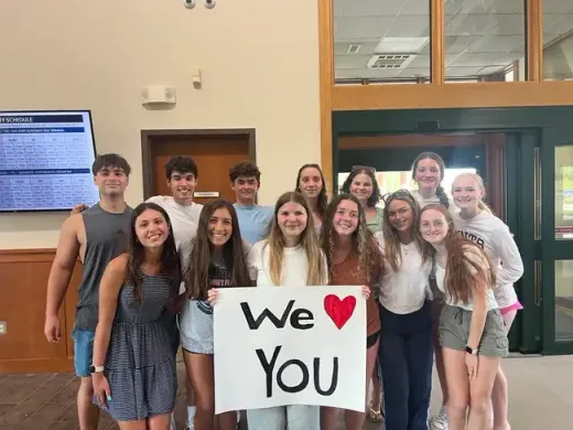 Grupo de alumnos posando en el vestíbulo del instituto con un cartel que dice We love you