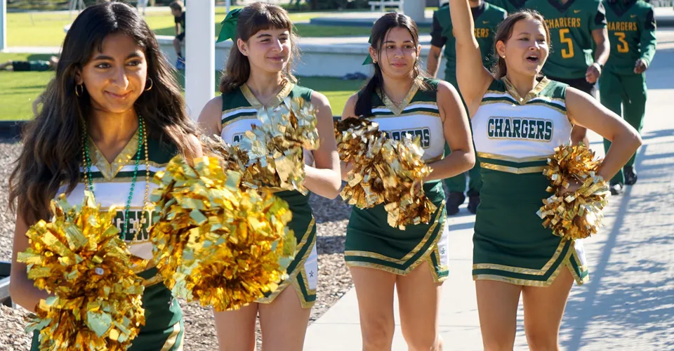 Un gruppo di cheerleader della Shorecrest Preparatory School si esibisce sul campo da gioco con lo stadio sullo sfondo.