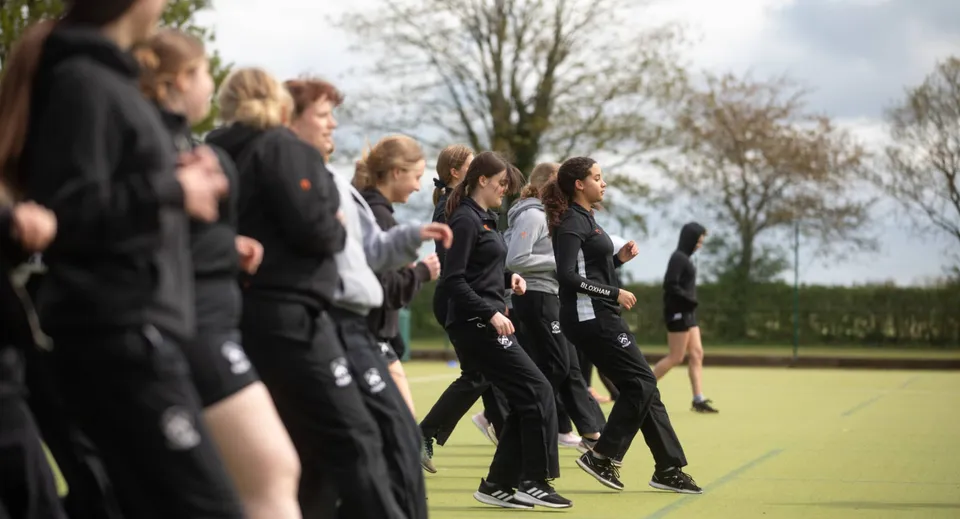 Un gruppo di studenti della Bloxham School sta su un campo d'erba davanti ad alcuni alberi.