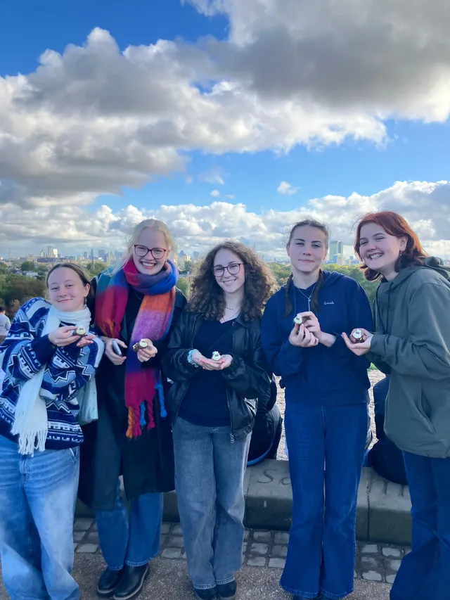 Cinco chicas con cupcakes en una colina con el perfil de la ciudad al fondo