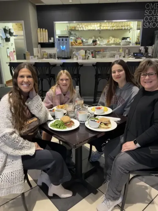 Quattro persone sorridenti a colazione al tavolo di un bar americano