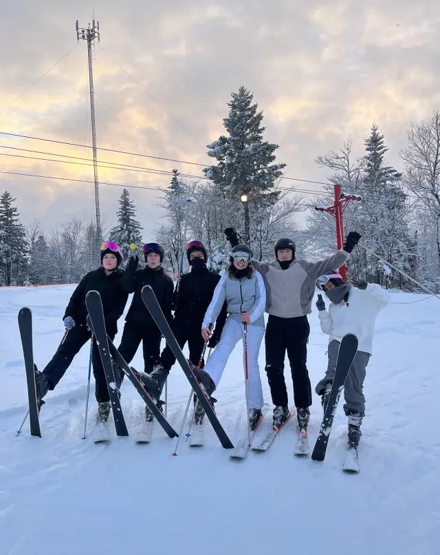 Sei studenti con sci e caschi in posa su una pista innevata al tramonto durante uno scambio in Canada