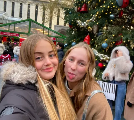 Due ragazze fanno una smorfia davanti a un grande albero di Natale in un mercatino negli Stati Uniti