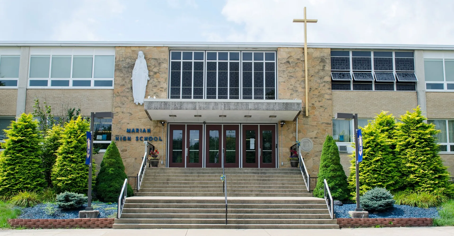 L'ampio edificio in mattoni della Marian Catholic High School con una croce sul tetto è circondato da aree verdi.