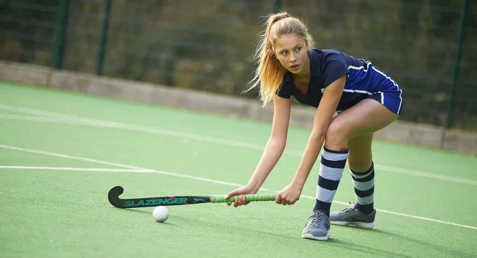 Una studentessa della Bethany School gioca a hockey su prato sintetico con la palla e la mazza.