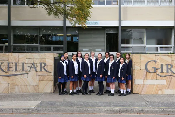 Un grupo de alumnas del Mackellar Girls Campus está de pie frente a un edificio con el letrero Mackellar Girls.