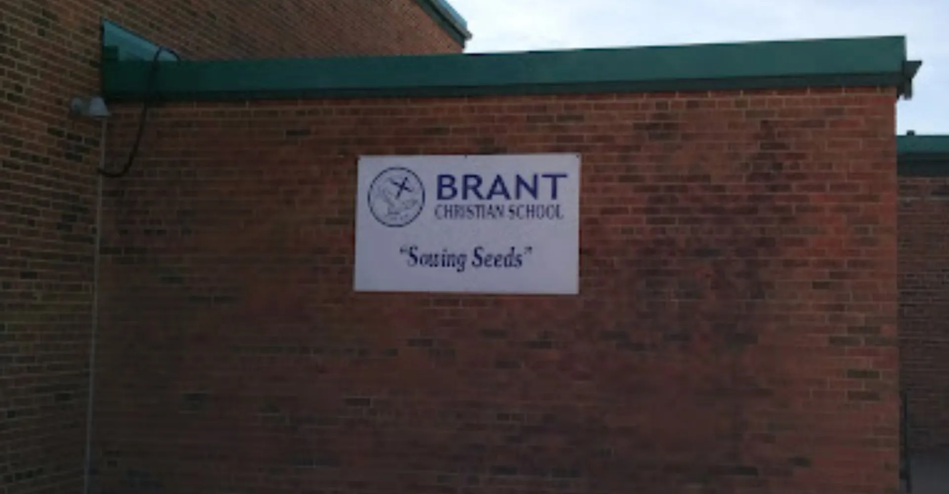 L'edificio in mattoni con il tetto verde della Brant Christian School mostra un cartello con la scritta Sowing Seeds.