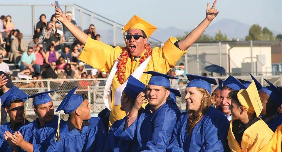 Un diplomato in toga gialla esulta a braccia alzate durante la cerimonia del Antelope Valley Union High School District.