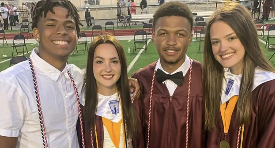 Quattro studenti della Bluefield High School sorridono insieme davanti al palco durante la cerimonia di diploma.