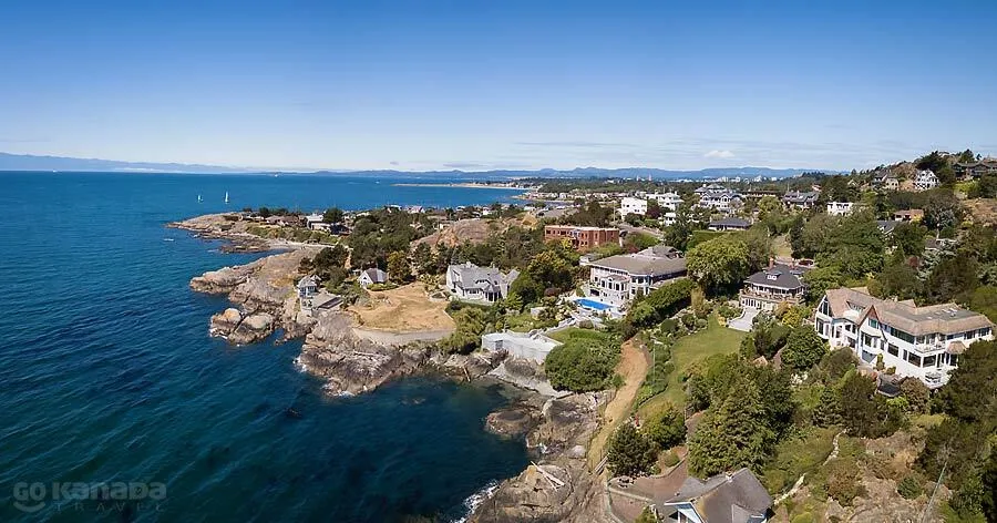 Costa rocosa arbolada con viviendas y el mar azul en la región de la École des Deux-Rives.