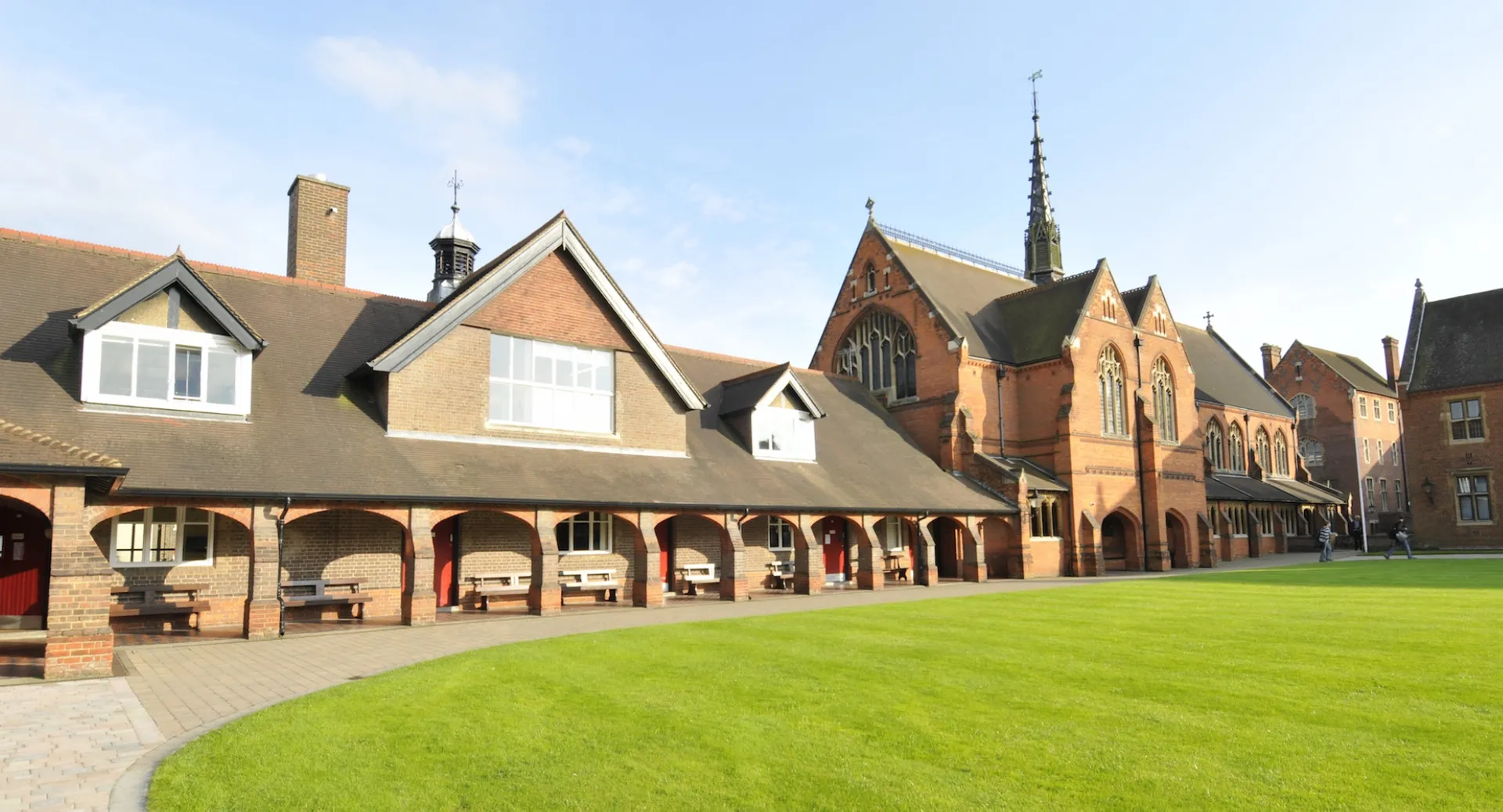Il cortile interno della Berkhamsted School mostra un prato circondato da uno storico edificio in mattoni con archi.
