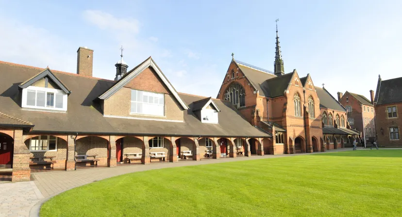 Il cortile interno della Berkhamsted School mostra un prato circondato da uno storico edificio in mattoni con archi.