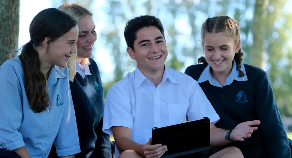 Un gruppo di studenti in piedi insieme che sorridono all'aperto nel campus del Pakuranga College.