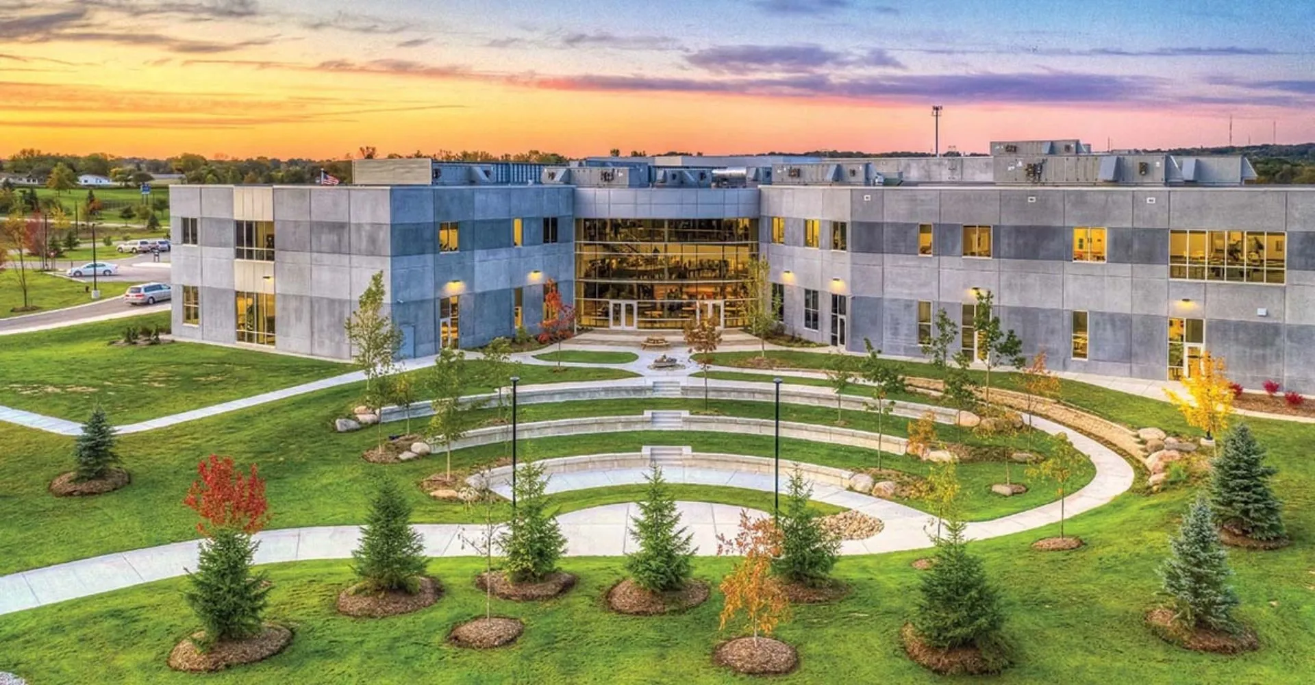 L'edificio moderno della South Christian High School si trova in un'area verde esterna con un percorso circolare sotto un cielo serale variopinto.