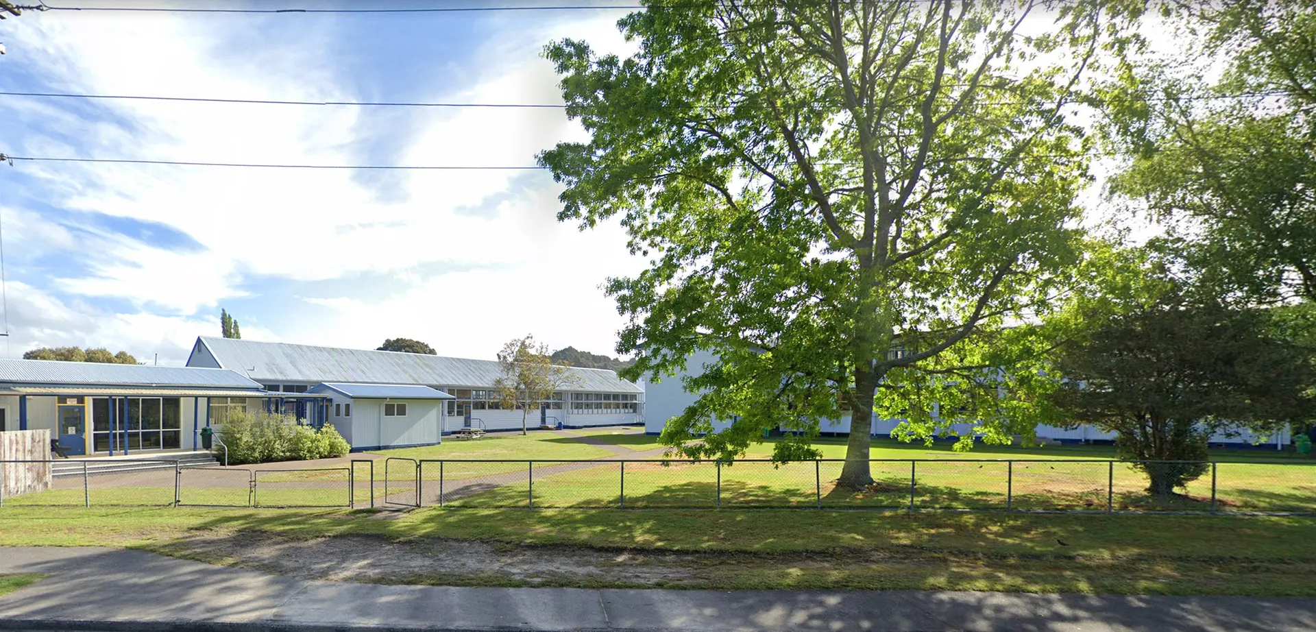 Un campo d'erba con alberi ed edifici sullo sfondo all'interno del campus della Taumarunui High School.