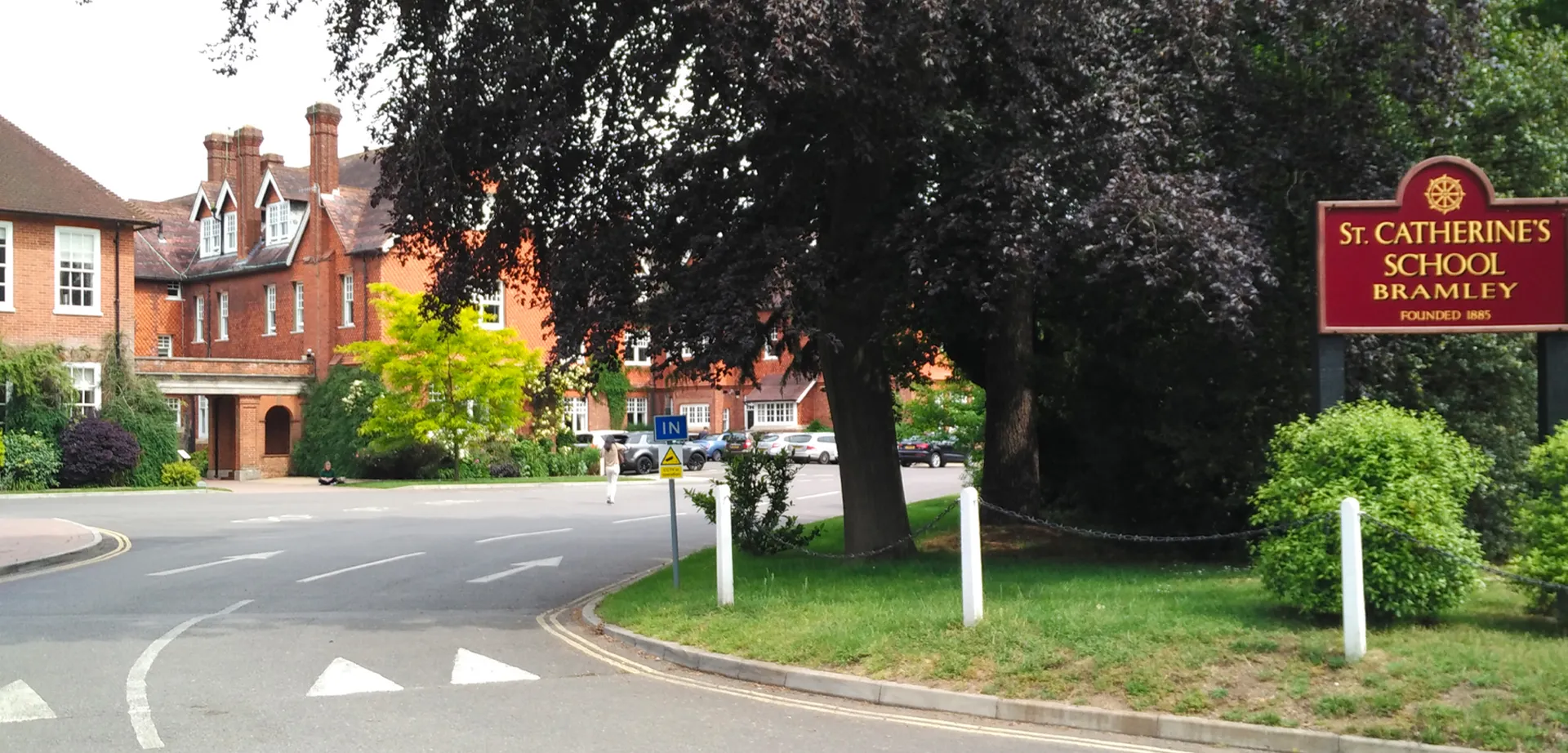 Una strada tranquilla con edifici in mattoni e un grande albero presso la St. Catherine's School.