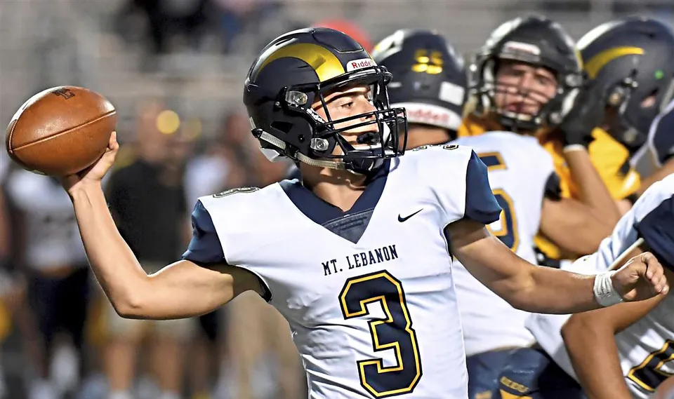 Un giocatore di football con maglia bianca numero 3 tiene la palla durante una partita notturna della Mount Lebanon High School.