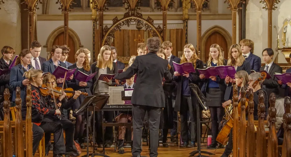 Un coro in toghe viola canta sul palco in una sfarzosa cattedrale nel campus della Gresham’s School.