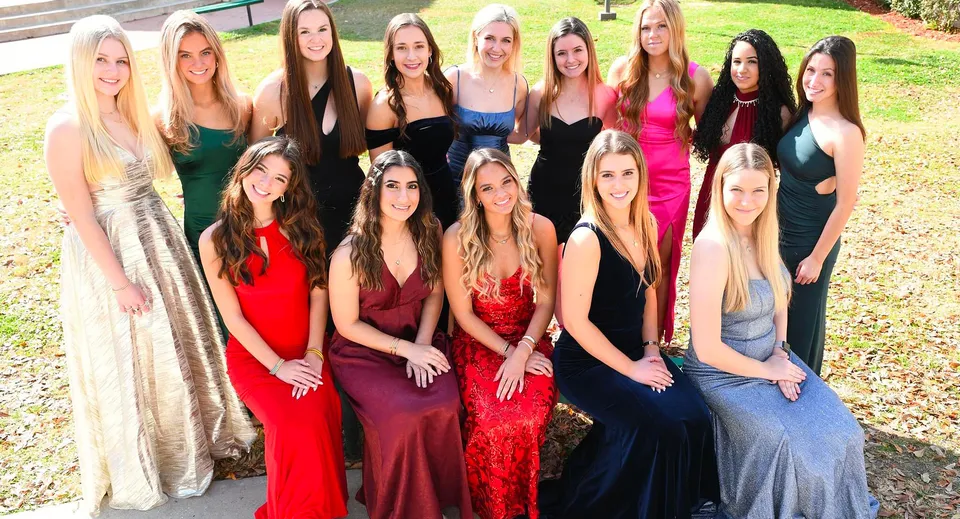 Un gruppo di studentesse della Trinity Catholic High School posa su un prato davanti a un edificio in mattoni.