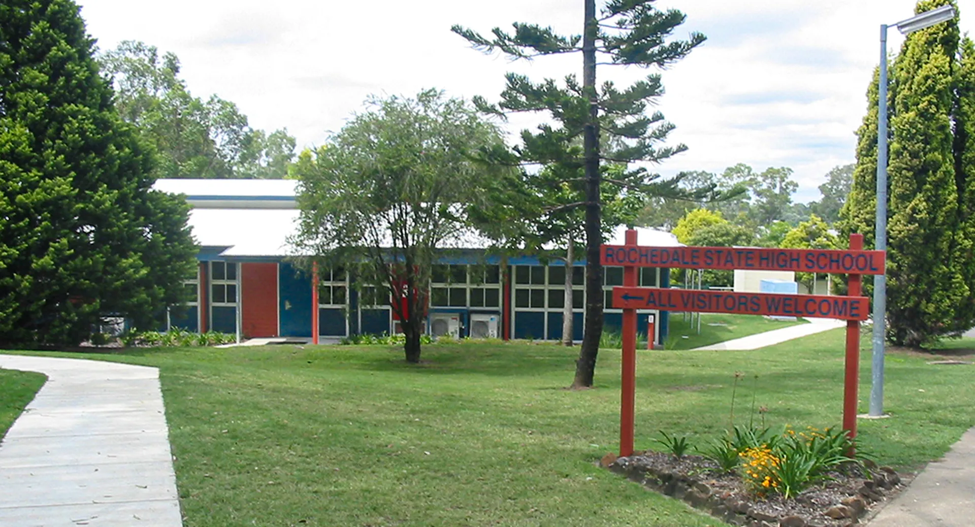 Il campus della Rochedale State High School mostra un edificio in mattoni rossi, circondato da alberi e un sentiero.