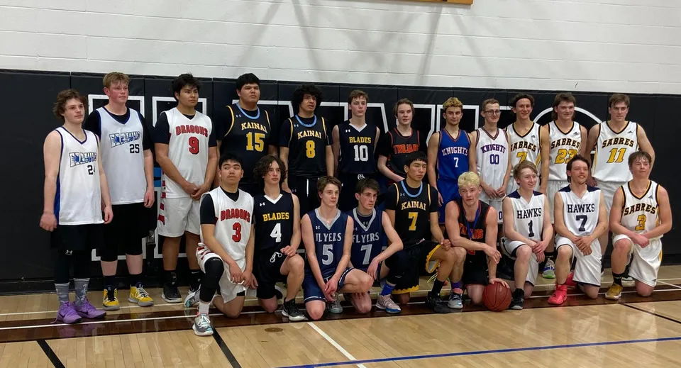 Un gruppo di giocatori di basket in posa insieme sul campo della J.T. Foster High School.