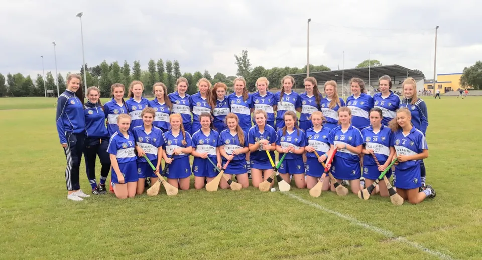 Un gruppo di giovani calciatrici in maglia blu sul campo sportivo del Castlepollard Community College.