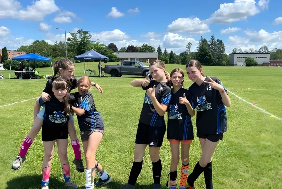 Un grupo de jóvenes atletas está en un campo deportivo en el recinto de la École secondaire publique Rivière Rideau.